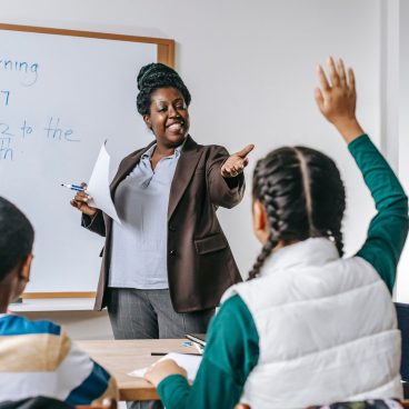 pexels-photo-5905923-5905923 Smiling African American woman offering schoolgirl to ask question during lesson in school classroom